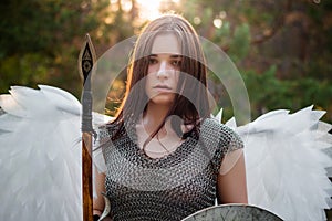 Portrait of a warrior woman in chain mail with steel bracers and wings behind her back.