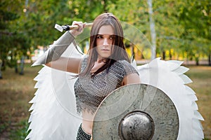 Portrait of a warrior woman in chain mail with steel bracers and wings behind her back.