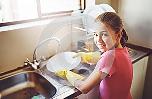 Portrait, washing dishes or kid with dirty plate and gloves in kitchen sink in home for healthy hygiene. Happy