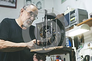 Portrait of a watchmaker repairing the machinery of an old clock