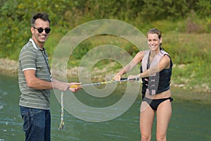 Portrait water skier holding rope with instructor