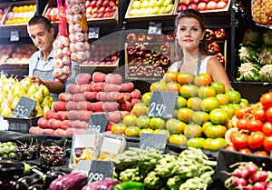 Portrait of welcoming female shop assistant and working male seller in fruit shop photo