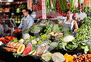 Portrait of welcoming female shop assistant and working male seller in vegetable shop photo