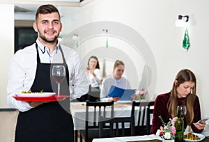 Portrait of welcoming waiter who is standing in restaurante