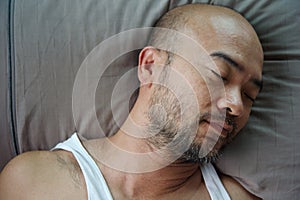 Portrait of bald beard Japanese sleeping man on grey pillow