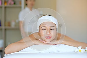 Portrait of White beautiful woman lie on bed in spa room and look relax and happy with Thai masseuse stand behind as background