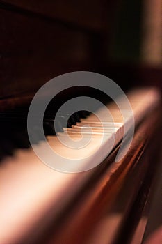 A portrait of the white and black keys of a beautifful old wooden piano. Some of the keys are worn out or have fallen off