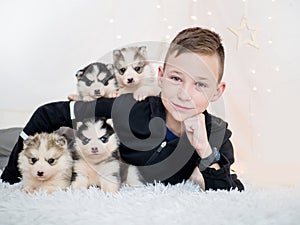 Portrait of a white boy and newborn husky puppies on white background