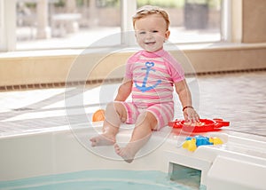 Portrait of white Caucasian baby girl laughing sitting on swimming-pool nosing photo