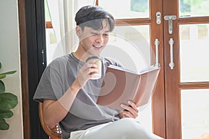 Portrait of a white man sitting inside the house reading and drinking coffee to relax on vacation