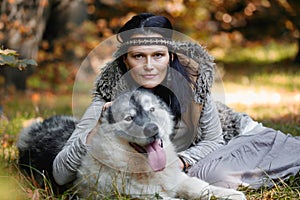 Portrait of a white pretty woman with an Alaskan Malamute dog in the forest