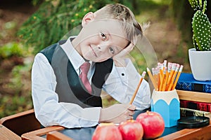 Portrait of a wistful first-grader boy sitting at a desk