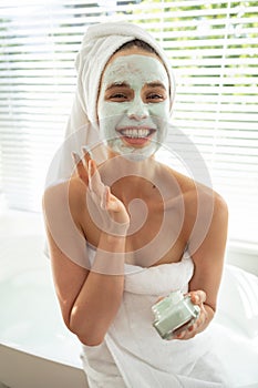 Portrait of woman applying face pack in bathroom