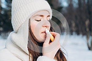 Portrait of woman applying lip balm in winter, copy space.