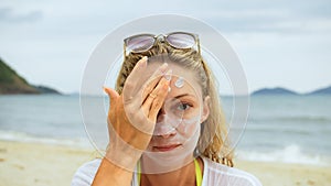 Portrait woman applying sun cream protection lotion.Woman looking at camera on beach near sea smearing sunscreen cream