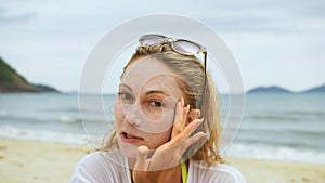 Portrait woman applying sun cream protection lotion.Woman looking at camera on beach near sea smearing sunscreen cream