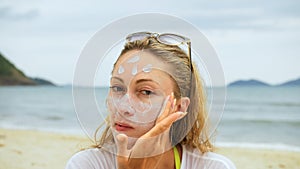 Portrait woman applying sun cream protection lotion.Woman looking at camera on beach near sea smearing sunscreen cream