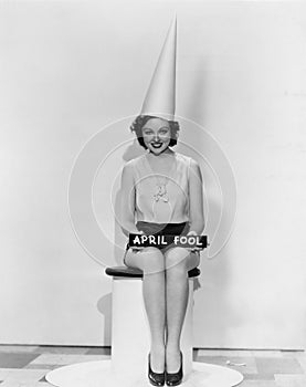 Portrait of woman with April Fool sign wearing dunce cap