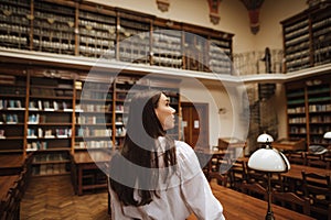 Portrait of a woman in an atmospheric public library looking away with a serious face