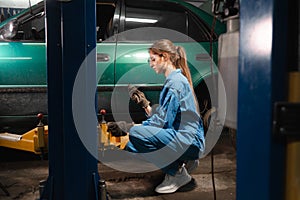 Portrait of a woman auto mechanic in working overalls and glasses. holding a nut in his hands. Baner