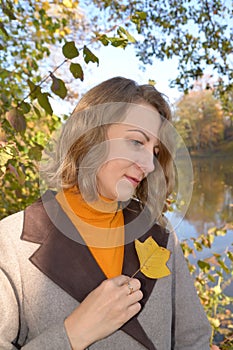 Portrait of a woman with an autumn leaf of tulip lyriodendron. Fall