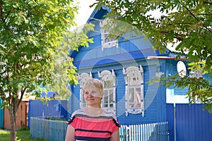 Portrait of the woman of average years against the blue wooden house