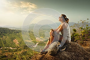 Portrait of woman with backpacker sitting on top of the mountain