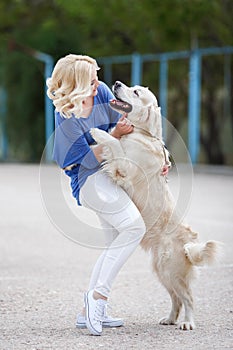 Portrait of a woman with beautiful dog playing outdoors.