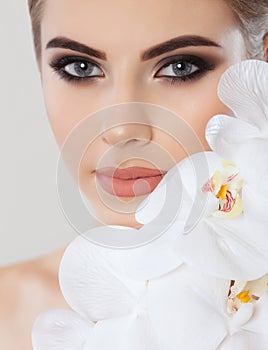 Portrait of a woman with beautiful make-up holds a white orchid in his hand