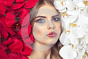 Portrait of a woman with beautiful make-up holds a white and red orchid in his hands.