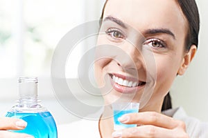 Portrait Of Woman With Beautiful Teeth Using Mouthwash In Bathroom