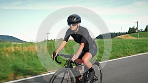 Portrait of woman on bike. Pro female cyclist descending on bicycle from uphill during cycling training. Triathlete riding road bi