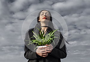 Portrait of woman in a black coat whose hair is flying in the wind stands in a field