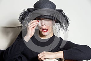 Portrait of a woman with black dress and hat looking sad