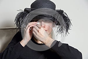Portrait of a woman with black dress and hat looking sad