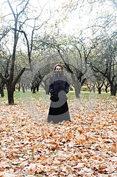 Portrait of a Woman in a black jacket and a long skirt with dreadlocks and a gas mask with spikes. Woman posing in