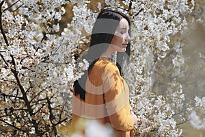 Portrait of a woman in blooming trees. Spring season specific. Dreamy. Sunny Day. International Woman& x27;s day. Blossom