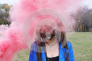 Portrait of a Woman in a blue jacket and dreadlocks in a gas mask with spikes. woman standing in smoke