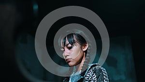 Portrait of a woman with braided hair, wearing armor, playing a grand piano and looking contemplative against a dark background