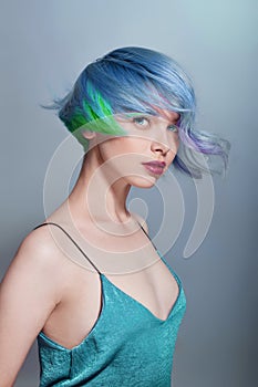 Portrait of a woman with bright colored flying hair, all shades of blue purple. Hair coloring, beautiful lips and makeup. Hair