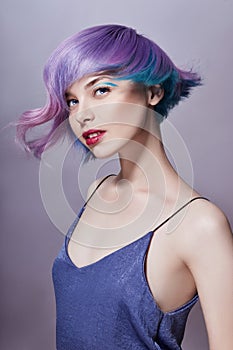 Portrait of a woman with bright colored flying hair, all shades of purple. Hair coloring, beautiful lips and makeup. Hair