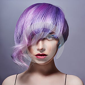 Portrait of a woman with bright colored flying hair, all shades of purple. Hair coloring, beautiful lips and makeup. Hair