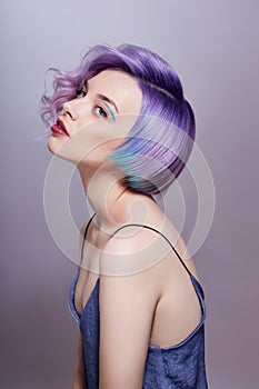 Portrait of a woman with bright colored flying hair, all shades of purple. Hair coloring, beautiful lips and makeup. Hair