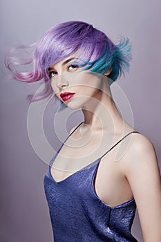 Portrait of a woman with bright colored flying hair, all shades of purple. Hair coloring, beautiful lips and makeup. Hair