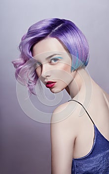 Portrait of a woman with bright colored flying hair, all shades of purple. Hair coloring, beautiful lips and makeup. Hair