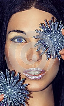 Portrait of woman brunette with Christmas decorations silver blue snowflakes. Fashion make-up.