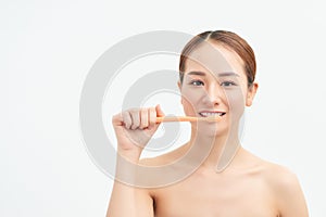 Portrait of woman brushing teeth on light background