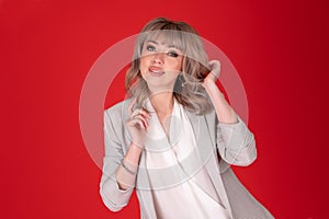 Portrait of a woman business blonde in bright jacket on redbackground .Copy space photo