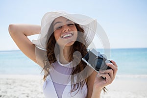 Portrait of woman with camera standing at beach