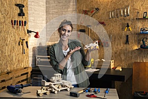 Portrait of woman in carpenter workshop showing wooden toys